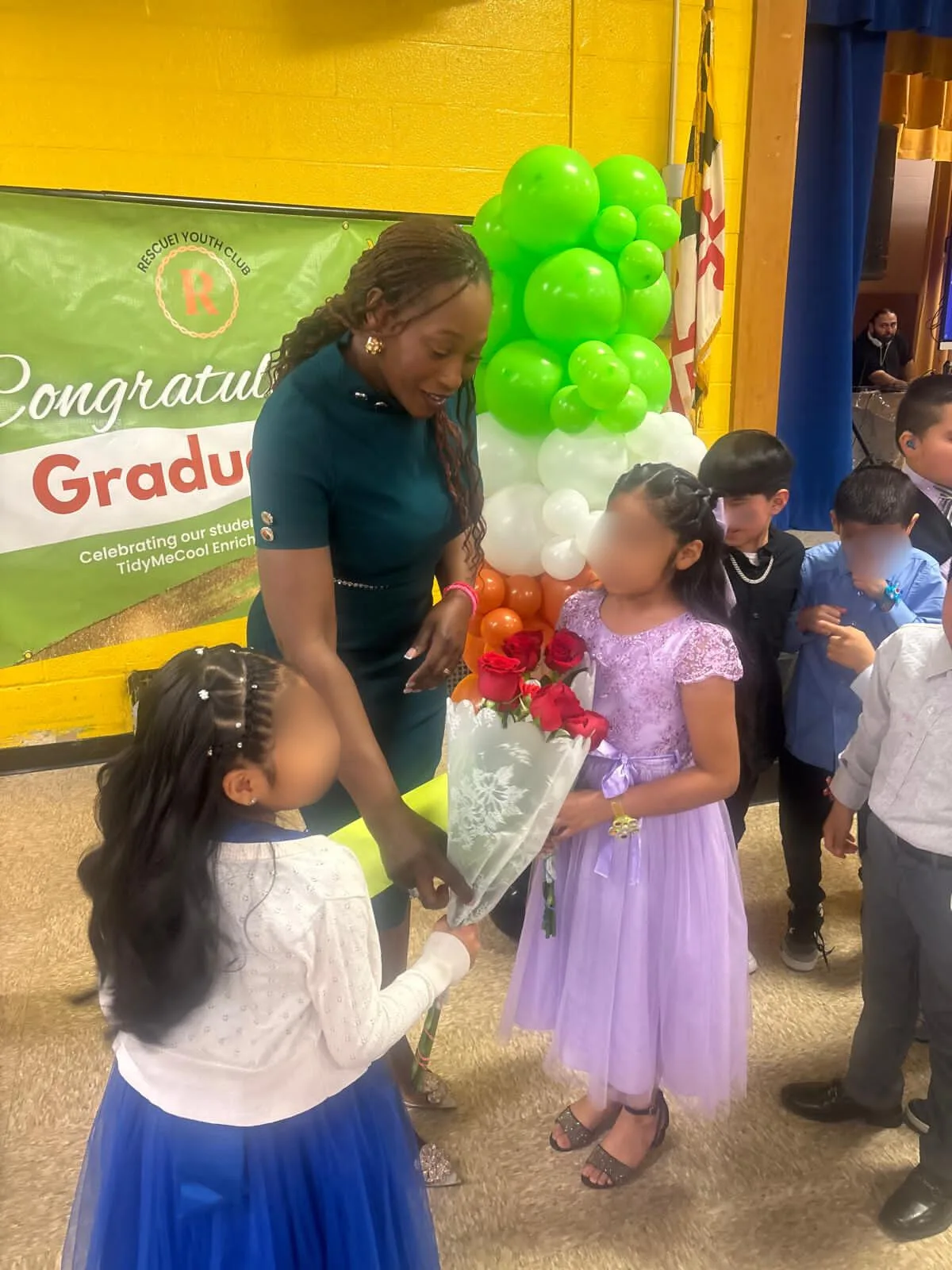 Children and program supporters celebrating beside graduation balloons