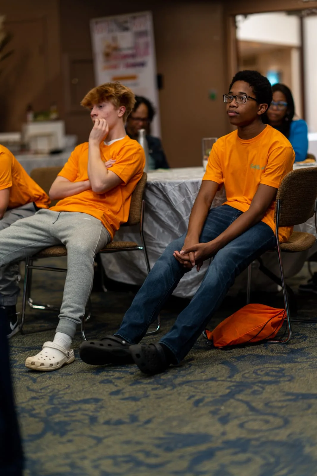 Students in orange program shirts seated during a session